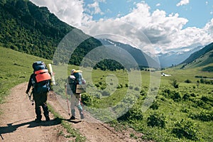 Two tourists going by the road at mountain green valley background