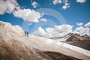 Two tourists, a man and a woman with backpacks and cats on their feet, stand on the ice in the background of the