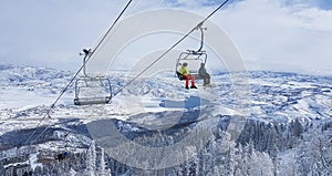 Two tourists skiing in Park City ride the chairlift to the top of the mountain.