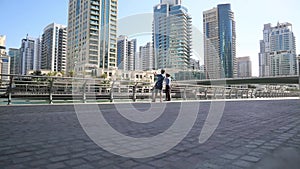 Two tourists stand on the embankment of a big city.