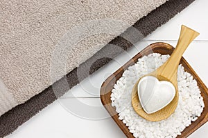 two towels with bowl filled with white bath salt and wooden spoon