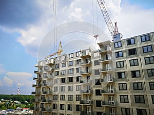 two tower cranes are building a high-rise monolithic-frame house at the construction site. Construction of apartments in