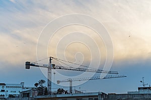 Two tower-type construction cranes on the background of a wide cyclonic cloud, changing weather conditions during photo