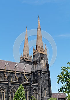 Two towers with spires opposite a blue sky