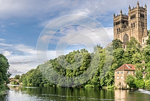 Two towers sticking up through a forest and a boat house and bridge