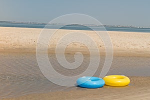 Two toy life preservers lying on the beach