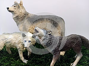 Three toy wolf figures on green grass