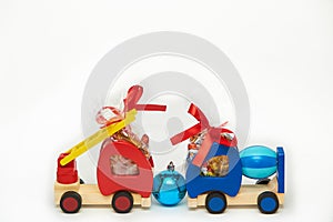 Two toy wooden trucks with gift chocolate and rainbow candies on the white background. Childhood