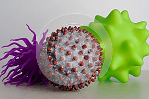 Two toys as a representation of virus or bacterias and one as a symbol of a SARS-CoV-2 virion