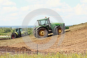 Two tractors at the silo compact freshly cut heavy corn with wheels, fermented corn will be used as cow feed in winter