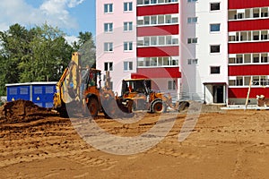 Two tractors work on construction site at summer sunny d