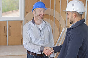 two tradesmen shaking hands inside property under renovation photo