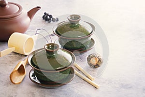 Two traditional Chinese porcelain green tea cups stand on a gray table.