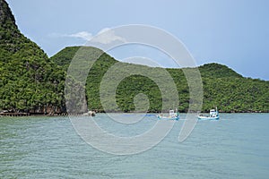 Two traditional fishing boat sailing pass a big mountain before go to port