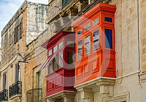 Two traditional Maltese enclosed wooden balconies painted in red and orange