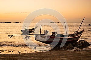 Two traditional wooden boats in a bright orange sunset, Ngwesaung, Myanmar