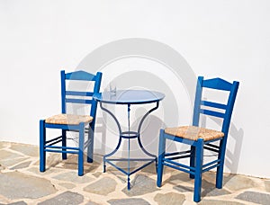 Two traditional wooden chairs and a metal table outdoors