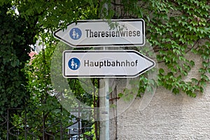 Two traffic signs `Theresienwiese` place of the octoberfest and `Hauptbahnhof` main station on the way between the main statio