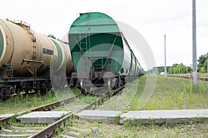Two trains with carriages stand on the railway crossing. Cargo wagons and tank cars on the rails close-up