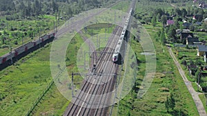 Two trains moving by rail in opposite directions through countryside, aerial