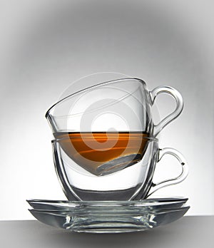 Two transparent cups and two transparent saucers on a white background