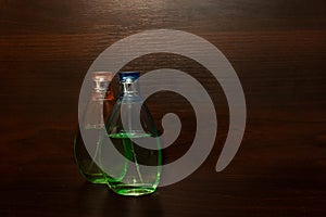 Two transparent glass bottle with pure liquid on wooden background with copy space. Closeup of perfume bottle