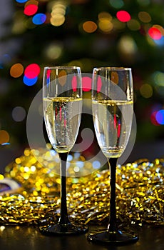 Two transparent glasses with black stems of champagne with bubbles