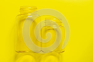 Two transparent plastic empty cans on a yellow background. Copy space