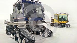 Two vehicles with four tracked wheels in the winter on the north slope, Alaska daytime photo