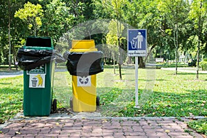 Two trash cans in the park.