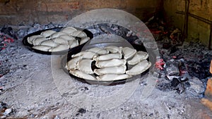 Two trays with traditional Argentinian empanadas cooking inside a clay oven