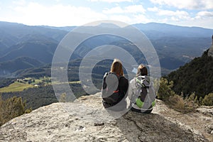 Two trekkers resting contemplating on the top of a cliff photo