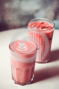 Two trendy beetroot lattes with latte art on table in cafe.