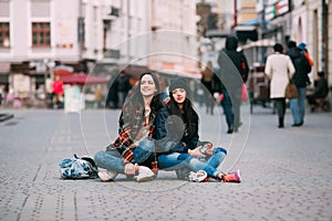 Two trendy and fashionable street girls skateboarders joking and smiling