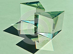 Two triangular glass cube prisms refract natural light into shade and shadow pattern.