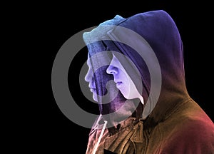 Two troubled teenage boys with black hoodie standing next to each other in profile isolated on black background. creative colorful