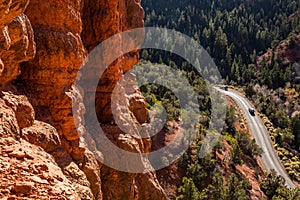 Two trucks driving up canyon road, looking down from red rock towers above