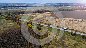 Two trucks on a highway between fields