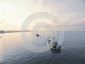 Two tugboat running in sea at sunset .