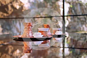 Two turkish coffee in copper cezve with piece of lokum on the glass table