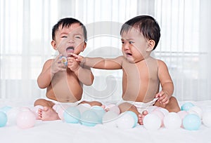 Two twin babies crying on bed