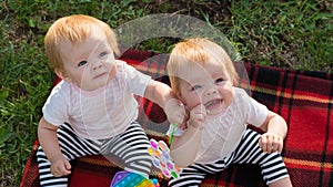 Two twins a blanket with bright toys look