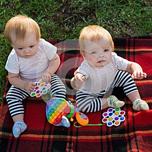 Two twins on blanket with bright toys look