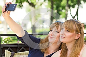 Two twins girls taking selfie in restaurant.