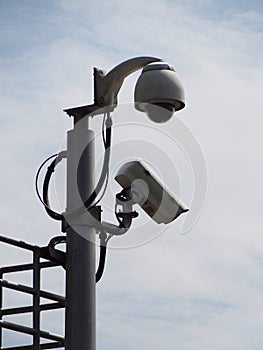 Two type of CCTV security camera install on high pillar against cloudy blue sky