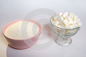 Two types of sugar, crumbly and cubes, white sugar on a white background