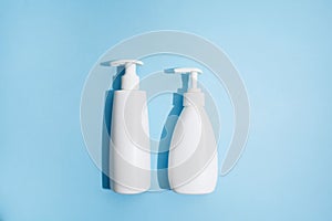 Two typy of white plastic bottles on blue background with hard light