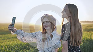 Two Ukrainian girls posing for selfies in a field.