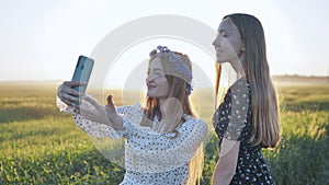 Two Ukrainian girls posing for selfies in a field.