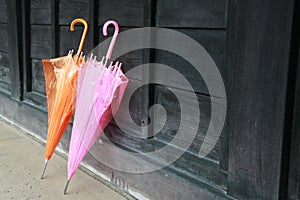 Two umbrellas lean on wood wall